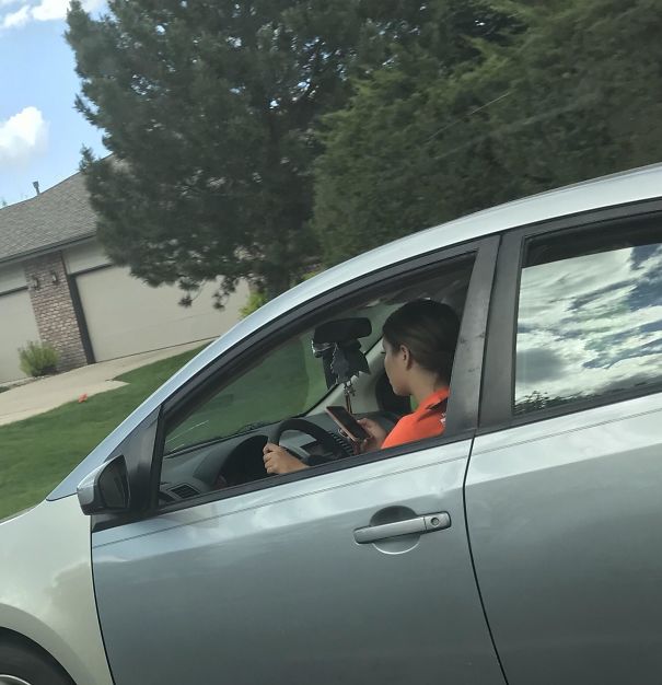 She Was Snapchating While Driving (40 Mph Road(64.4 Kph)). She Also Had A Little Brother In The Passenger Seat While Doing This. Hate How Often I See People Doing Stuff Like This (Photo Taken By A Passenger Of My Car)