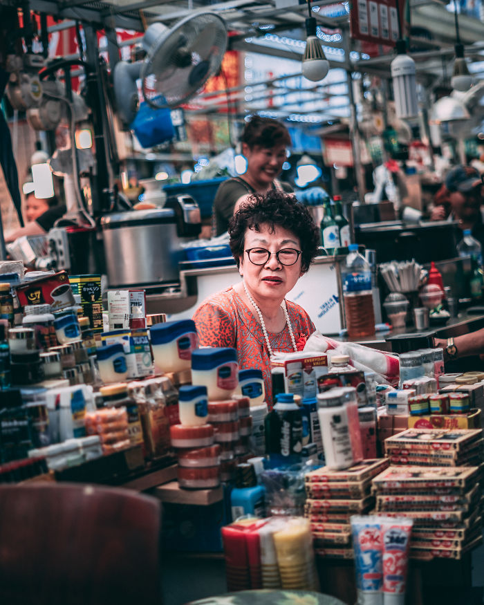 Older woman selling various products at a busy market in Seoul, showcasing daily life as an English teacher living in Korea.