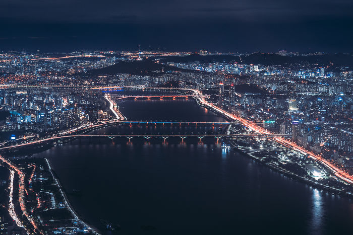 Nighttime aerial view of Seoul cityscape with illuminated bridges and busy roads, captured by an English teacher living in Seoul.