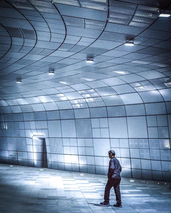 Person walking alone inside a futuristic, curved architectural space in Seoul, showcasing English teacher life and city photos.