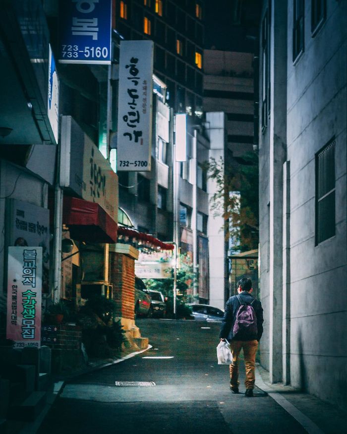 Person walking down a narrow Seoul street at night, capturing city life as an English teacher in South Korea.