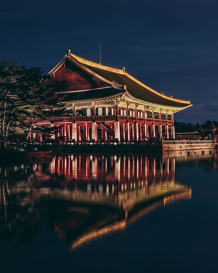Traditional Korean palace in Seoul lit up at night, reflecting on calm water, showcasing the city's cultural heritage for English teachers.