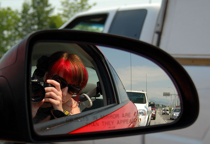 Women doing selfie on the front mirror of the car
