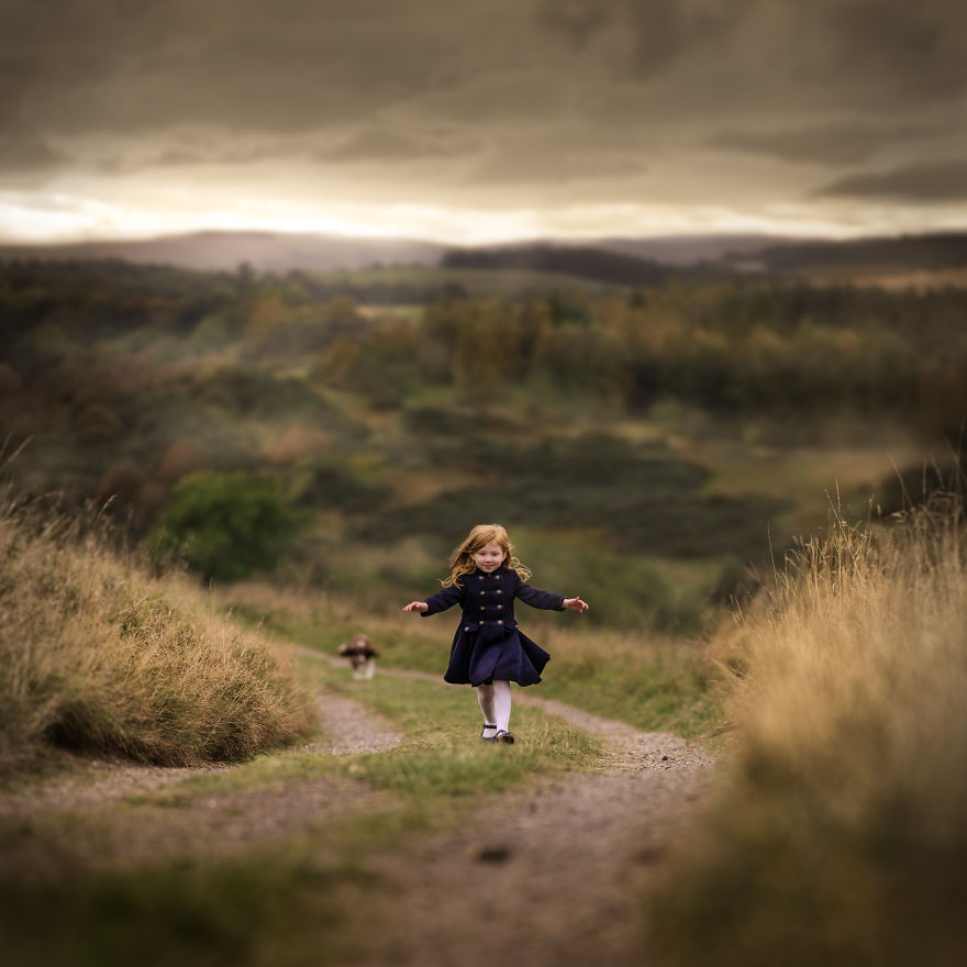 Scotland - A Girl Running Uphill With A Beautiful Scottish Views Behind Her