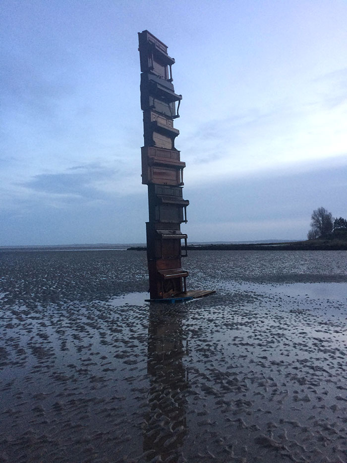 Pila de pianos en una playa con marea baja