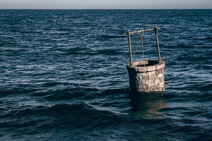Water Well Drifting In The Open Ocean. Pejac's Latest Art Installation 'Land Adrift' Brings A Disturbing Mirage Of A Post-Apocalyptic Future