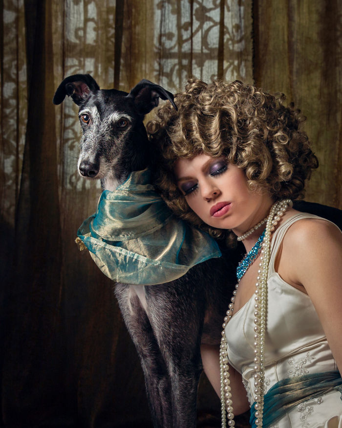 Portrait of a woman with curly hair posing with an abandoned hunting dog in Spain, both wearing vintage-style accessories.