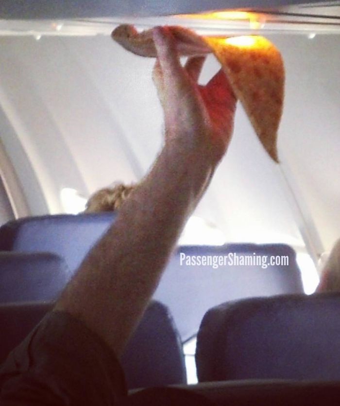 Un tipo intentando calentar su pizza con la calefacción del avión
