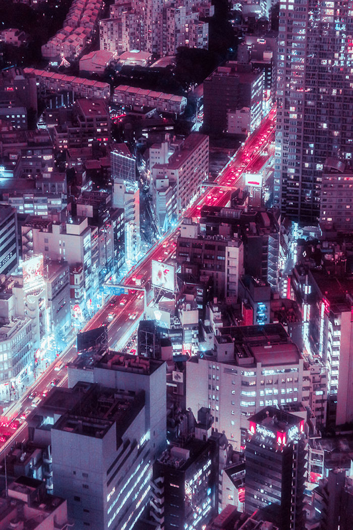 Aerial night view of Tokyo cityscape with illuminated buildings and vibrant neon-lit streets.