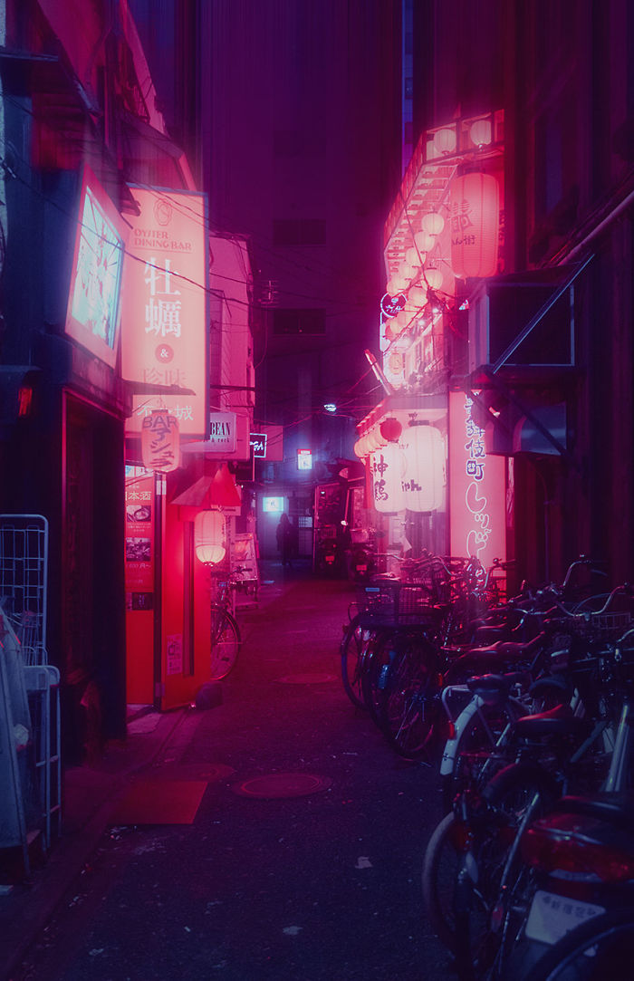 Night street scene in Tokyo with glowing neon signs and bicycles, captured on a dream trip with a camera.