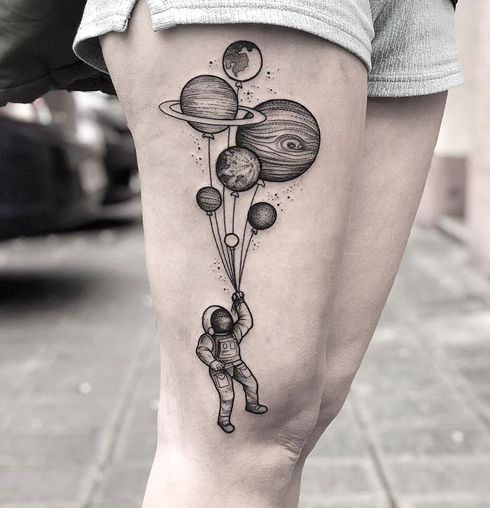 Spaceman holding planets leg tattoo