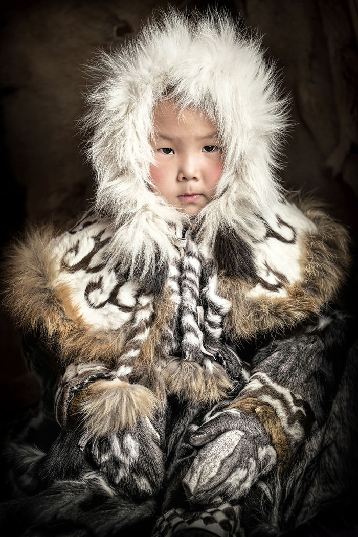 Child from indigenous people wearing traditional fur clothing in inaccessible corners of the world, captured during travels.