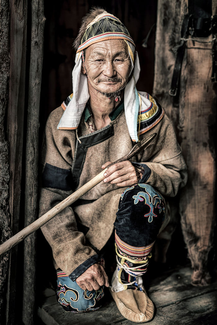 Indigenous man in traditional clothing holding a wooden spear, photographed in an inaccessible corner of the world.