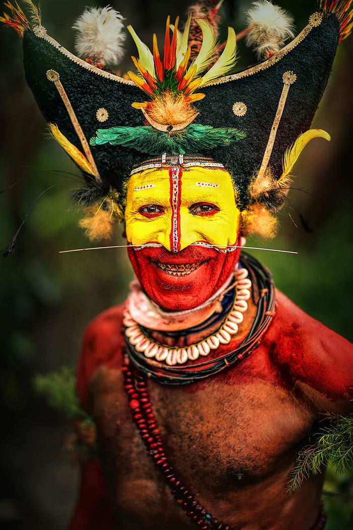 Indigenous man with traditional face paint and elaborate headdress in inaccessible corners of the world portrait photograph