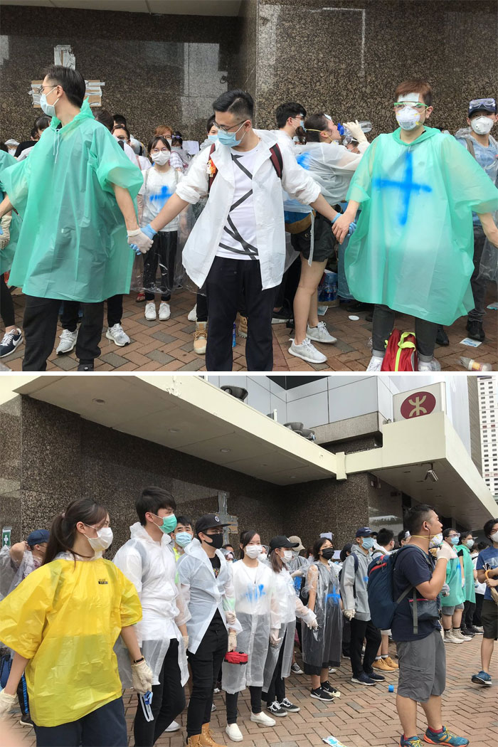 Volunteers In Ponchos Marked With A Blue Cross, Wearing Surgical Masks And Goggles, Form A Human Wall To Protect The First Aid Area Right Outside Admiralty Station, Across The Street From The Hong Kong Central Government Offices