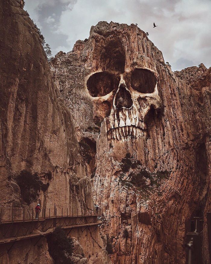 Skull-shaped rock formation on a cliff, a person walks on a bridge, surreal visual metaphor in dreamlike atmosphere.