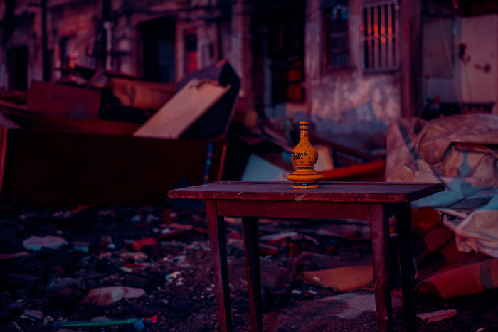 Old Shikumen lane house interior with a wooden table and decorative vase amidst debris in a historic Shanghai street.