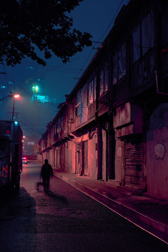 Night view of a Shikumen lane house street in Shanghai with dim lighting and a solitary pedestrian walking.