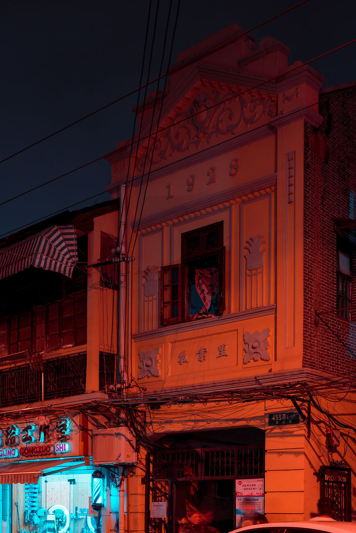 Historic Shikumen lane house built in 1928 lit by red and blue lights on a Shanghai street at night.
