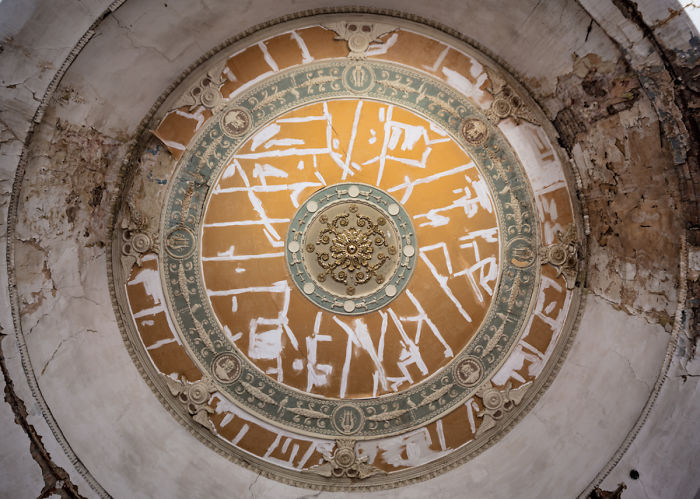 Ornate and decaying ceiling dome with faded paint and detailed moldings in an abandoned place in Tbilisi.