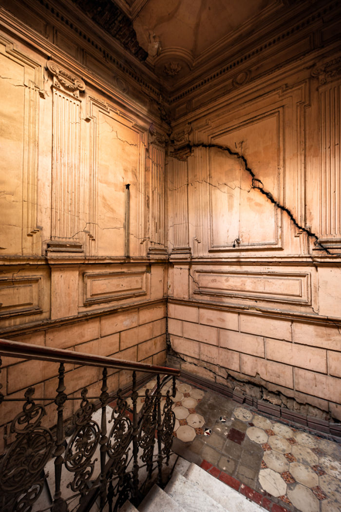 Abandoned places in Tbilisi showing c*****d walls and detailed wrought iron railing on old staircase interior.