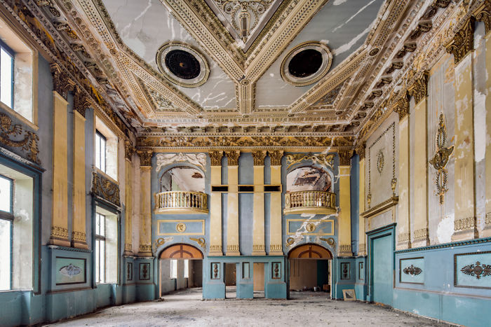 Interior of an abandoned ornate building in Tbilisi with peeling paint and intricate architectural details visible.
