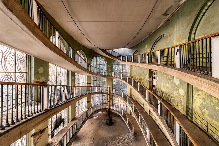 Interior view of an abandoned building in Tbilisi with curved balconies and large arched windows showing decay and neglect.