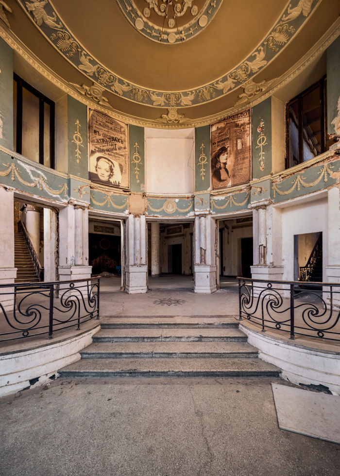 Interior of an abandoned place in Tbilisi with ornate wall decorations and peeling paint showing signs of decay.