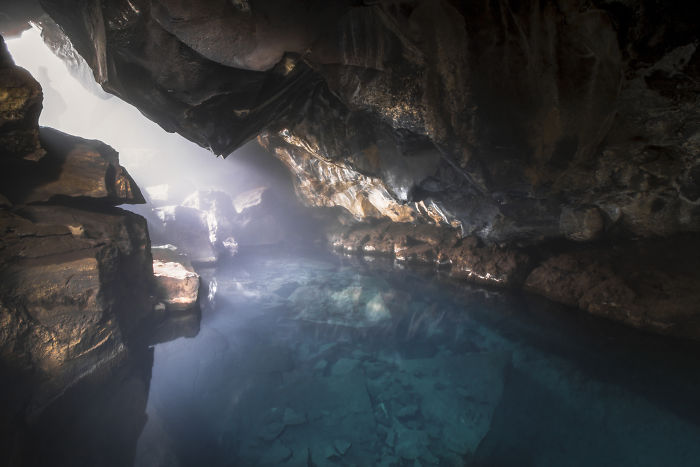 Underground geothermal pool with clear blue water inside a rocky cave showcasing Iceland natural beauty.