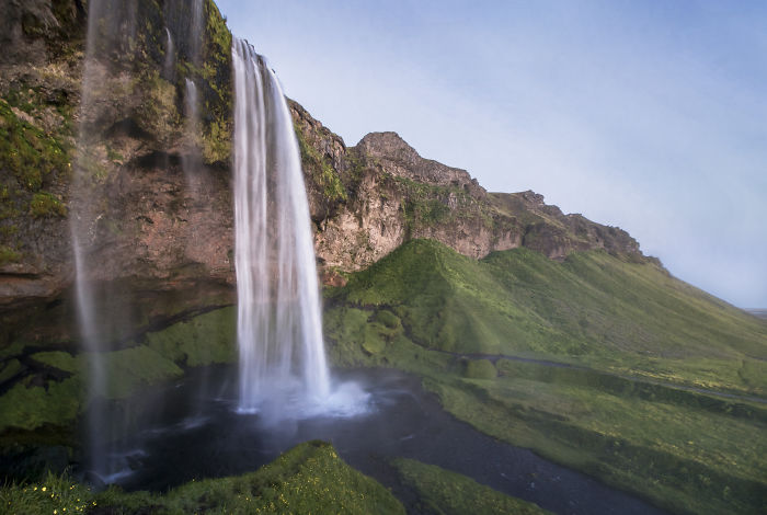 Seljalandsfoss waterfall cascading over rocky cliffs surrounded by lush green landscape in Iceland's natural beauty.