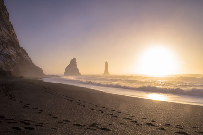 Iceland black sand beach at sunrise with ocean waves and rock formations capturing natural beauty.