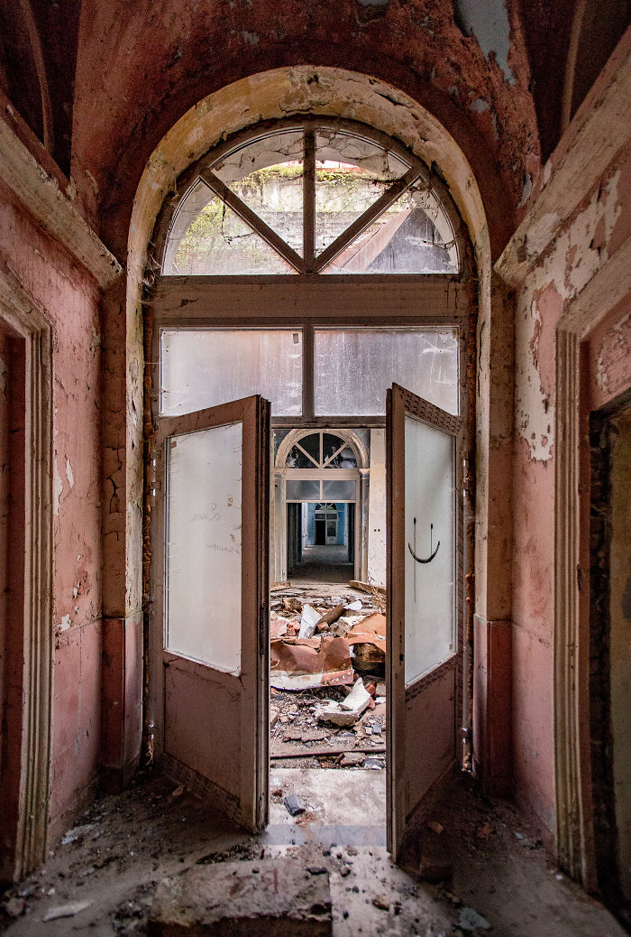 Abandoned thermal baths in Romania showing a decayed corridor with broken doors and debris inside the historic building.