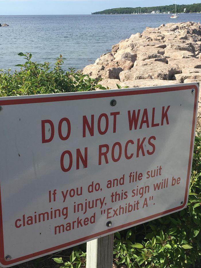 No caminar por las rocas. Si te caes y nos denuncias, este cartel será la Prueba A