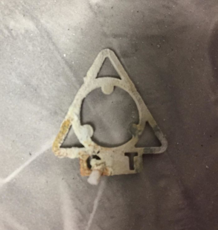 Found Inside Cremated Remains. Triangular Less Than An Inch Tall And Wide. C And T At Bottom. Did Not Burn So Possibly Metallic. Felt Flexible