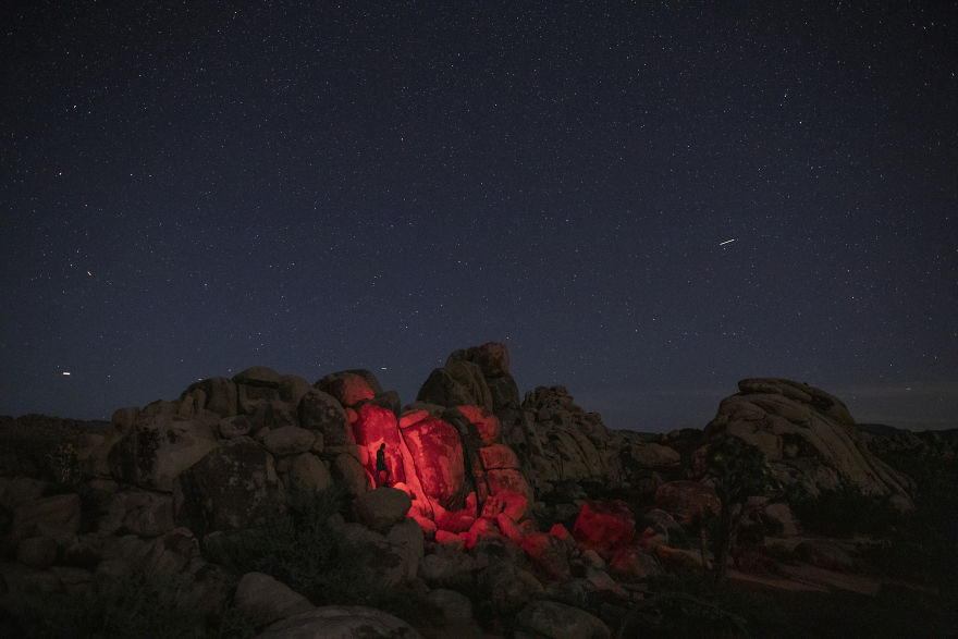 Silhouette of a man lit up on the rocks at night