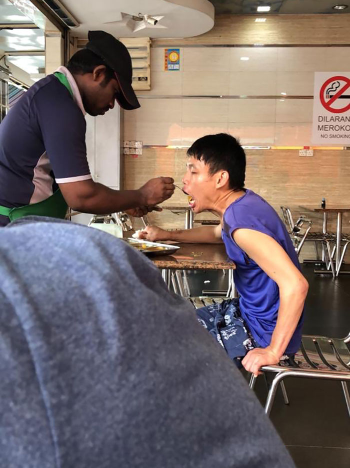 A Waiter At A Local Restaurant Feeding A Man With Special Needs. God Bless Them Both