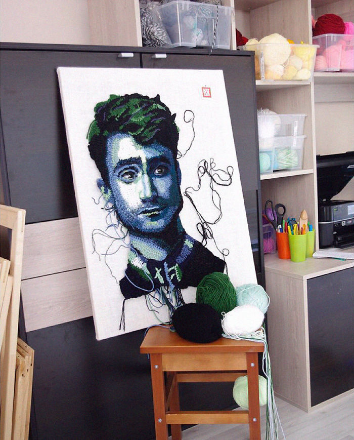 Crochet artist's detailed portrait in progress with yarn balls in studio, showcasing intricate crochet art techniques.