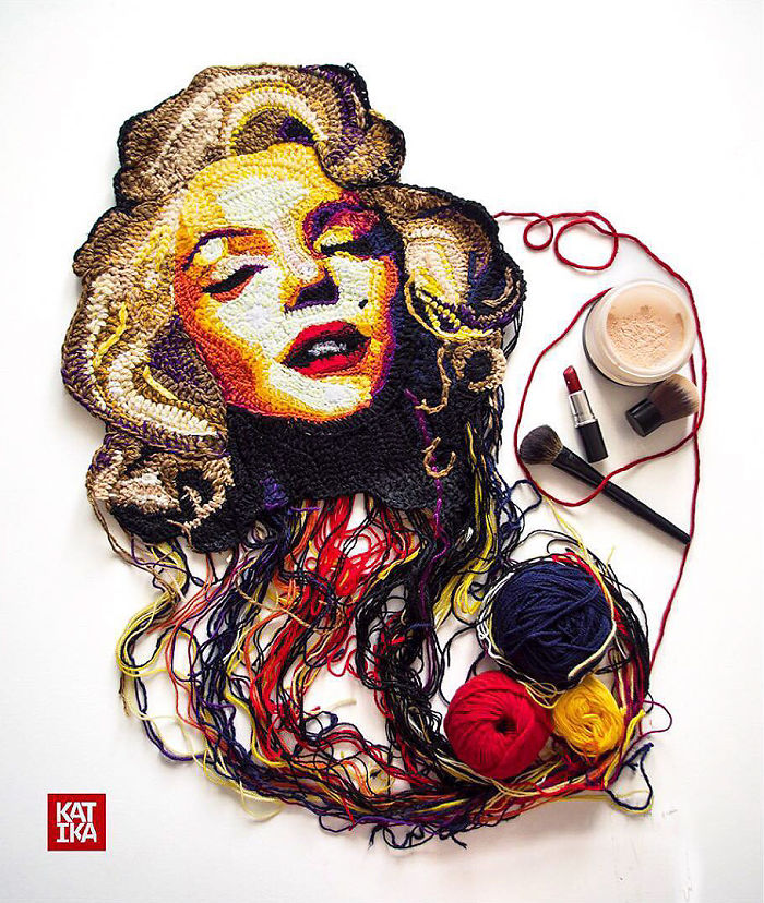 Crochet portrait of a woman with blonde hair alongside sewing yarn balls and makeup brushes in artistic display.