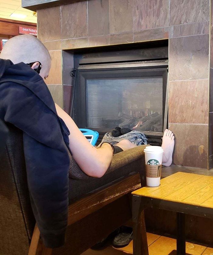 Drying His Socks By The Fireplace In A Coffee Shop