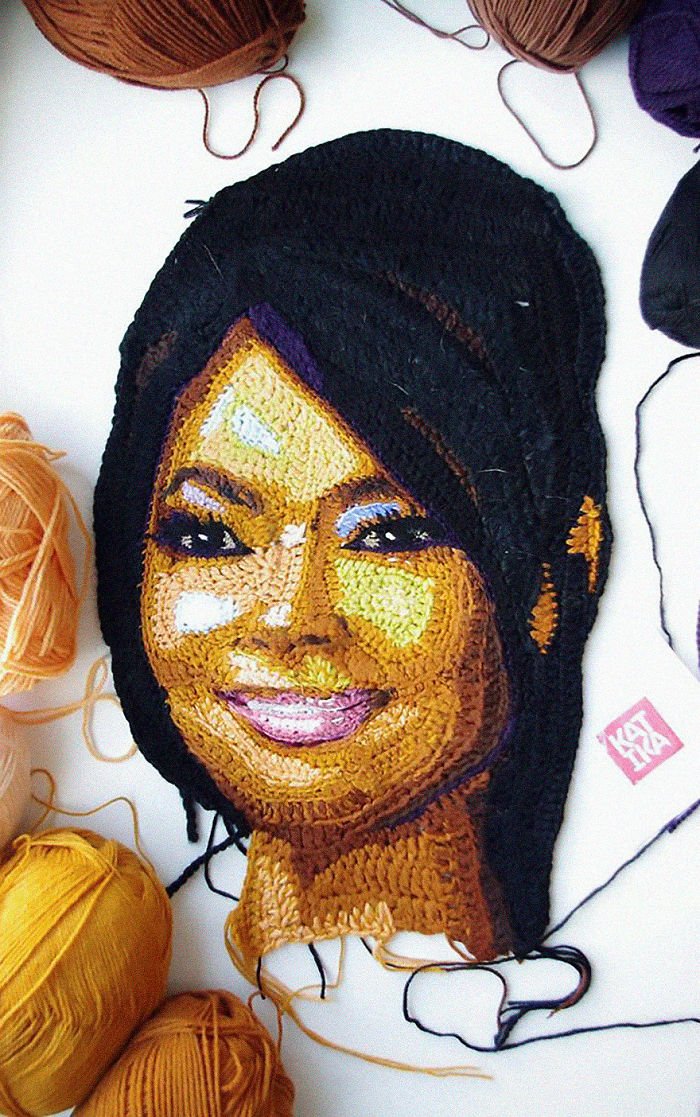 Crochet portrait of a smiling woman surrounded by yarn balls, showcasing detailed crochet art by a crochet artist.