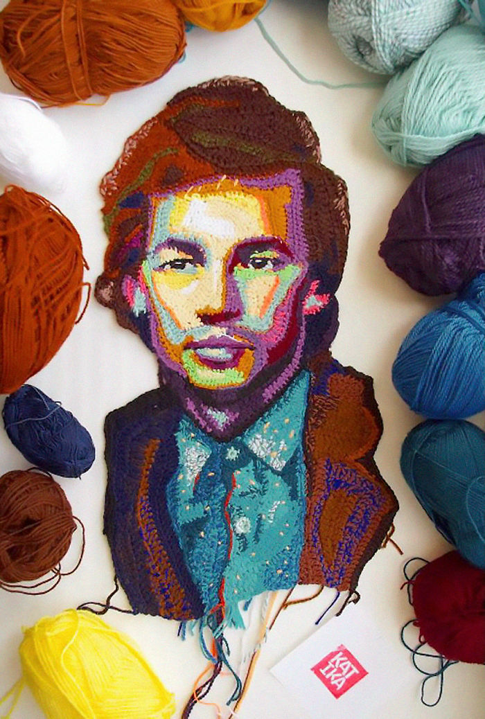 Colorful crochet portrait surrounded by yarn balls, showcasing detailed crochet art and vibrant handmade portrait design.