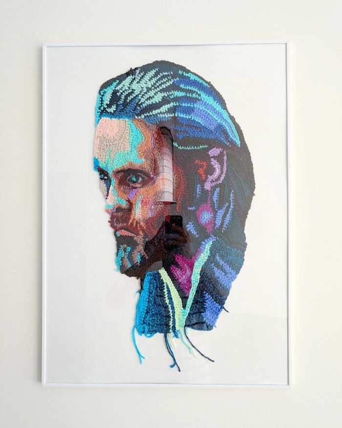 Crochet portrait artwork of a bearded man with blue hair, showcasing detailed and colorful yarn artistry.