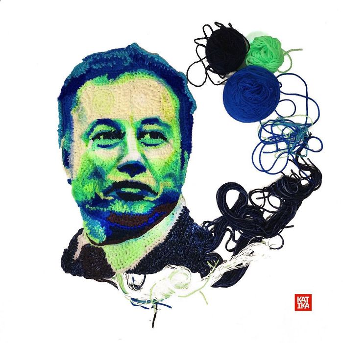 Crochet portrait of a man’s face in blue and green yarn with balls of yarn beside it by crochet artist.