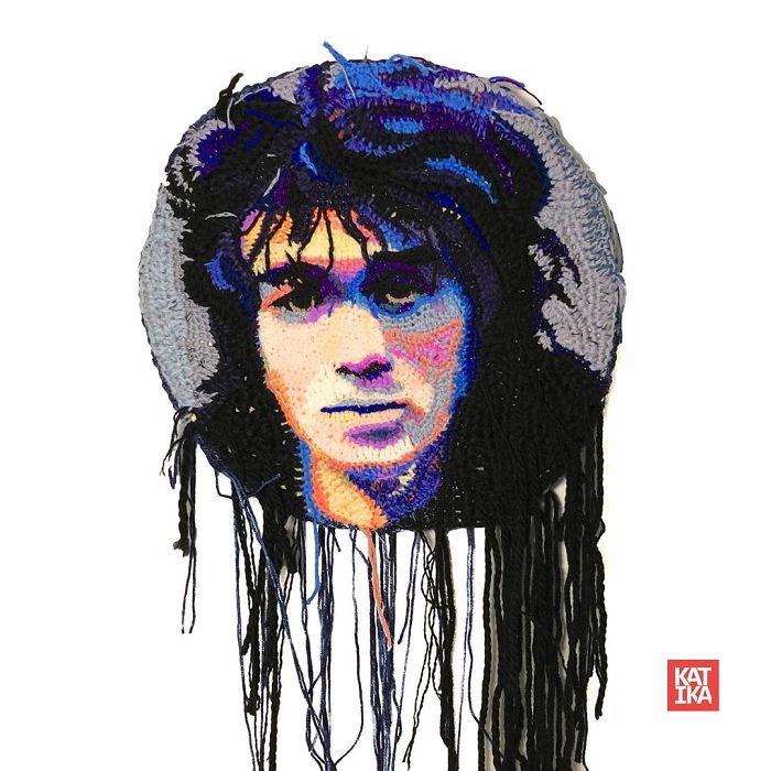 Crochet artist portrait artwork of a person with curly hair in blue, black, and gray tones with hanging yarn strands.