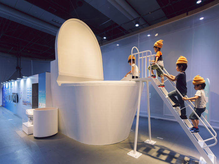 Japanese Children Wearing Feces-Shaped Hats Slide Into A Giant Toilet