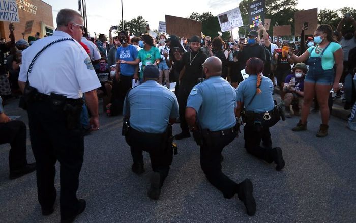 Police Officers From Ferguson, Missouri, Join Protesters To Remember George Floyd By Taking A Knee In The Parking Lot Of The Police Station On Saturday