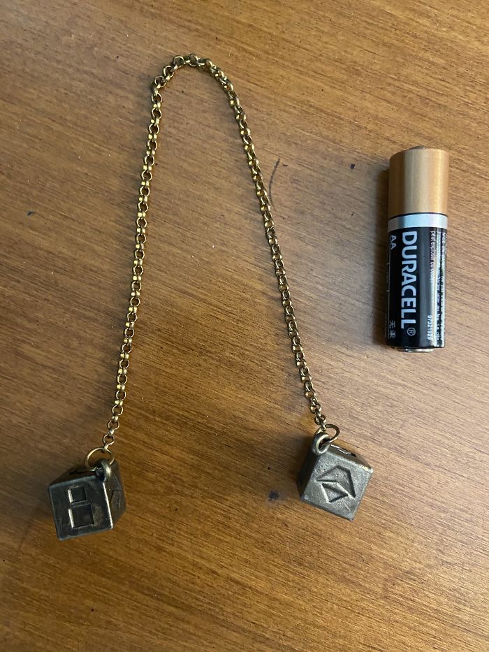 Heavy Metal Cubes On The End Of Chain With Different Shapes On Each Side Of The Cubes. Aa Battery For Scale. What Is This Thing?