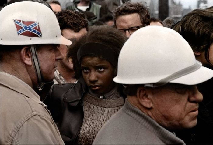 Aprox. 1960: Manifestación por los derechos civiles. Mujer negra mirando a un hombre con la bandera confederada en su casco