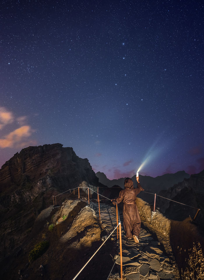 Person holding a flashlight on a mountain path at night under a starry sky in Madeira adventure trip.