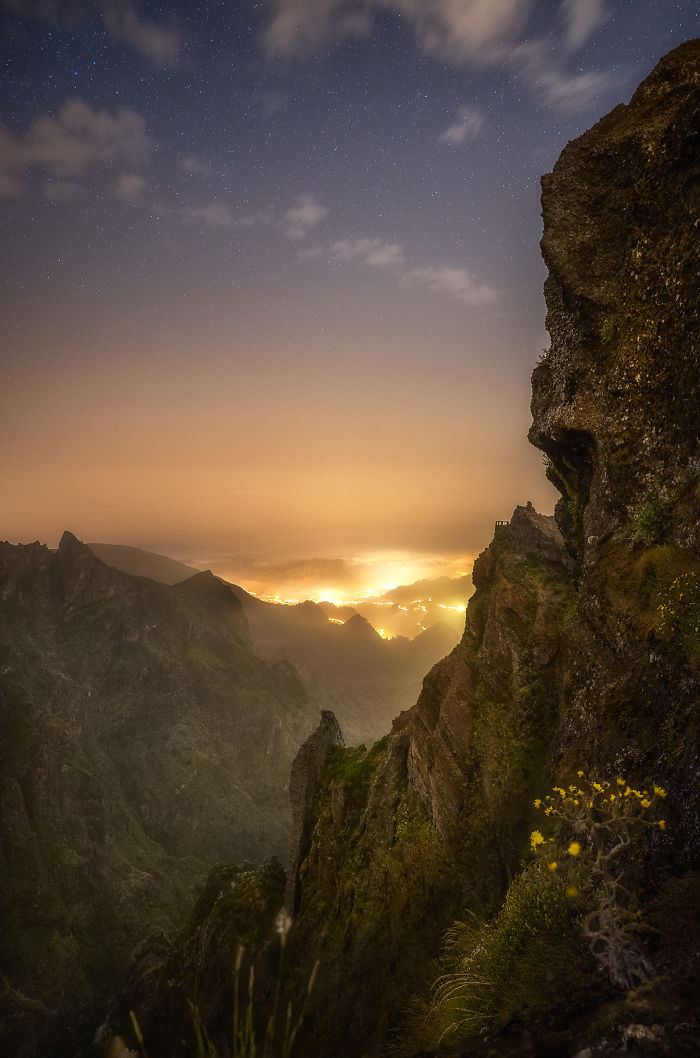 Night sky filled with stars over rugged mountains and glowing lights in Madeira, showcasing magical scenery and landscape views.